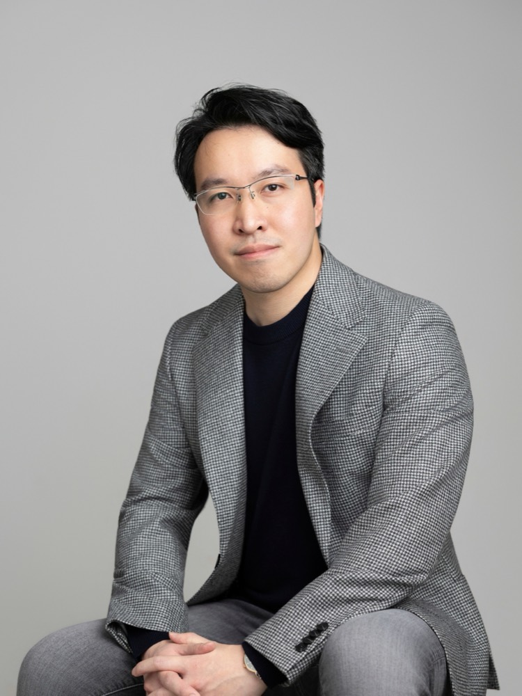 Ed Hung, seated, in a grey houndstooth blazer